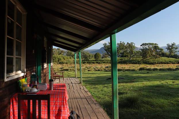 the front porch of a Mount Kenya accommodation hut with a setup table on a sunny morning